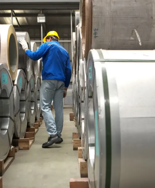 Industrial worker inspecting inside a large metal tube in a factory wearing safety helmet and gloves